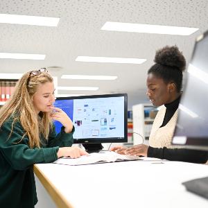 Two people talk to each other in the library of the faculty of economics.