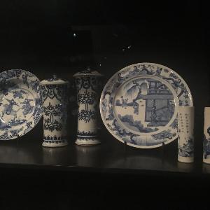 Vitrine mit weiß-blauem Porzellangeschirr, darunter ein Teller und eine Schale