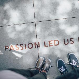 Zwei Fußpaare stehen vor einer Inschrift ´Passion led us here´