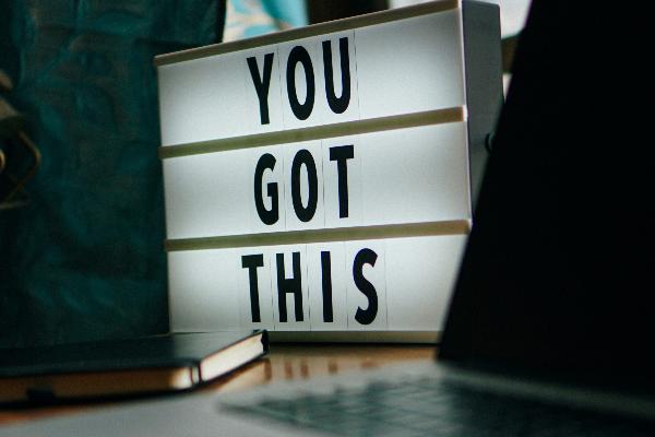 Schreibtisch mit verschiedenen Utensilien und Leuchtkörper mit Schriftzug ´YOU GOT THIS´