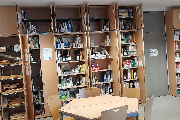 Raum mit geöffneten Schränken voller Bücher, Ordner und Lernmaterialien