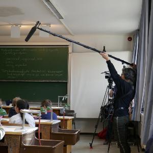 Foto einer Unterrichtsaufzeichnung mit Schulklasse und Kamerateam mit Tonangel