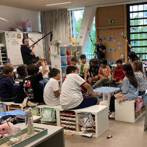 Foto einer Unterrichtsaufzeichnung mit Schulklasse im Sitzkreis und Kamerateam