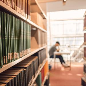 Fakultätsbibliothek Psychologie und Pädagogik (LMU) mit Student (unscharf, am Tisch) zwischen Bücherregalen