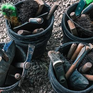 Vier Eimer voll mit Werkzeug, wie Spatel, Handbesen und kleinen Schaufeln.