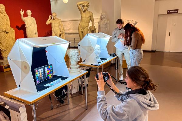 Photo of students scanning and photographing statues in a museum.