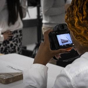 Student holding a camera and taking picture of an object