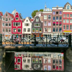 Brücke über einen Kanal in Amsterdam mit bunten Häusern im Hintergrund
