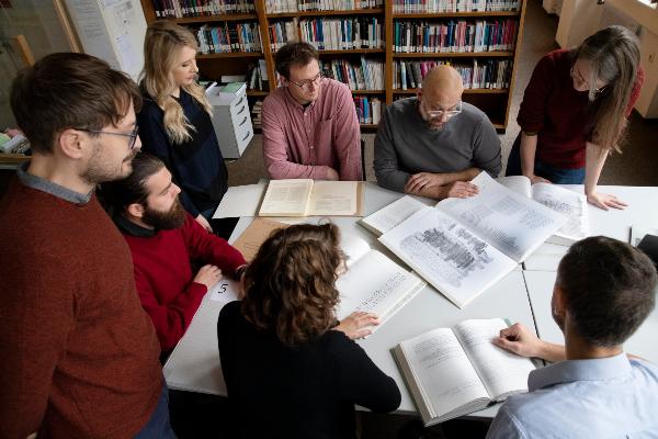 Studierende mit Dozent über Schriften gebeugt