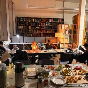 Studierende und Dozierende sitzen gemeinsam in der Bibliothek und lesen.