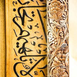 Arabische Schrift auf gelbem Holz mit einer Zierleiste rechts.