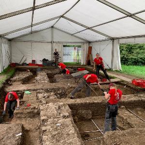 Studenten, die auf der Lehrgrabung in Kempten unter einem Pavillion arbeiten und römische Mauern ausgraben.