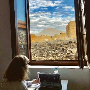 Frau schaut aus dem Fenster auf freigelegte Häuser von Pompeji