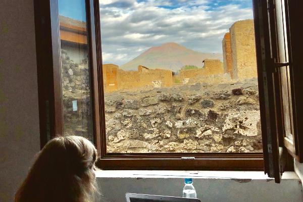 Frau schaut aus dem Fenster auf freigelegte Häuser von Pompeji