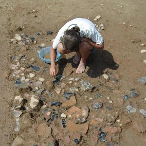 Archäologische Ausgrabung mit einem Mann der viel Keramik Scherben freipräpariert.