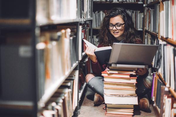 Promovendin vor einem Bücherstapel