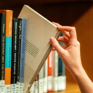 Hand, die ein Buch aus einem Bücherregal nimmt