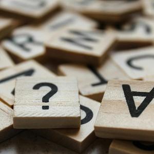 Buchstabensteine mit Fragezeichen im Vordergrund