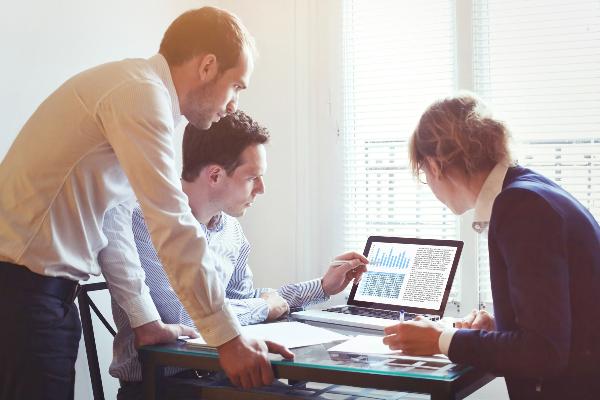 Group of professionals discussing something over laptops and documents.
