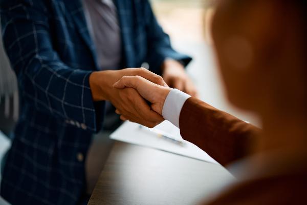 Close-up of a hand handing over a job application envelope.