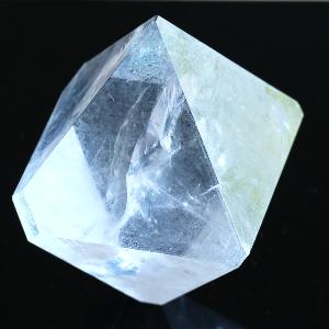 Transparent colorless alum crystal against a black background