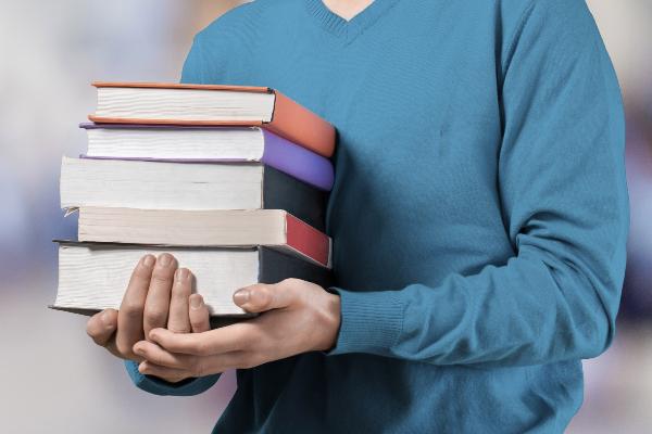 Symbolic image: A person carrying a stack of books