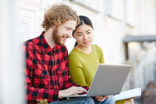 Symbolic image: A young woman and a young man sitting in front of a laptop
