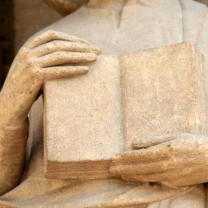 Eine Steinfigur hält ein Buch.