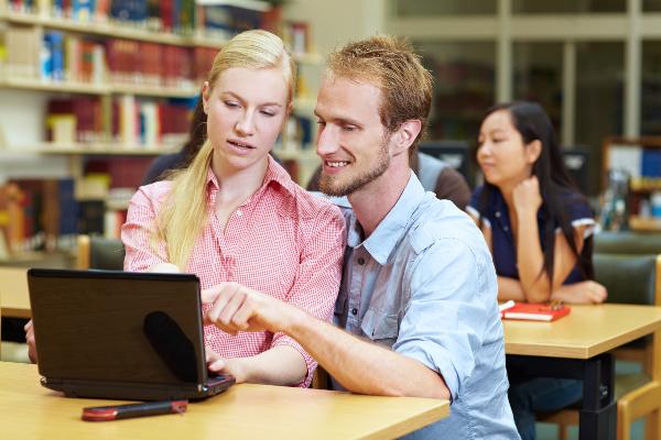 Symbolbild: Eine junge Frau und ein junger Mann sitzen vor einem Computer.