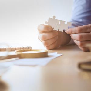Symbolbild: Eine Hand hält zwei Puzzle-Teile.