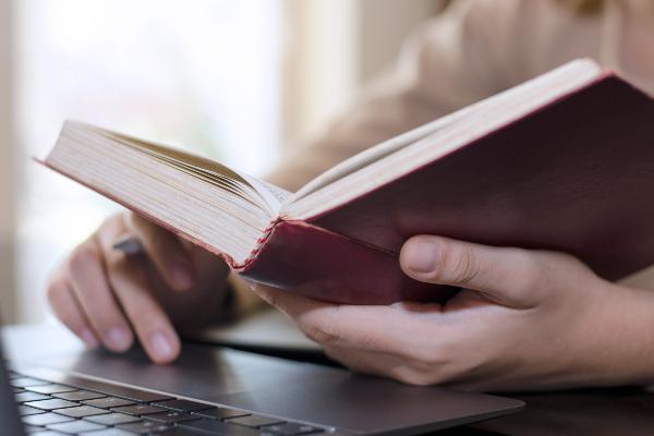 Symbolbild: Eine Person hält ein aufgeklapptes Buch in der Hand.