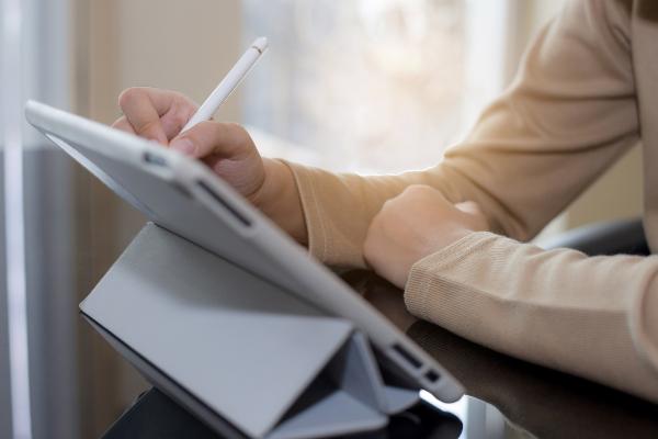 Symbolbild: Eine Person schreibt auf einem Tablet.