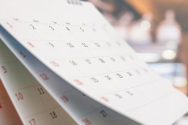 Close-up white paper desk calendar with blurred bokeh background date and business meeting concept