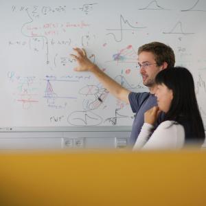 GSN students discussing in front of whiteboard