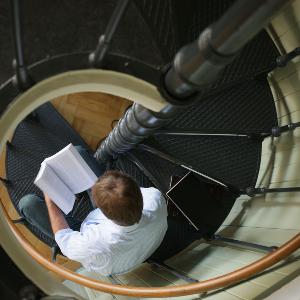 Researcher on spiral staircase in the philosophy library of the LMU