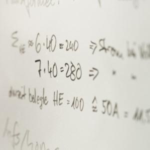Mathematical equations written in black marker on a whiteboard