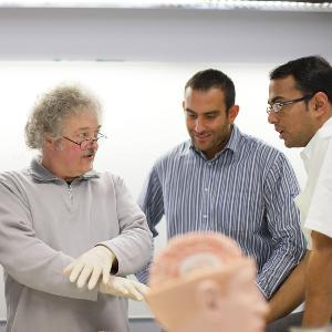 Course instructor discussing with students, out of focus brain model in front