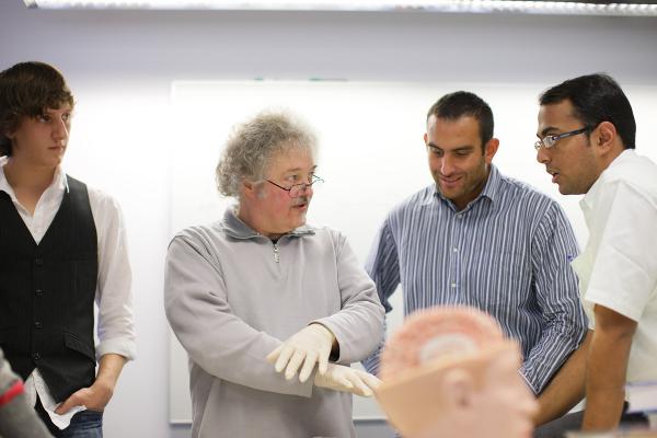 Course instructor discussing with students, out of focus brain model in front