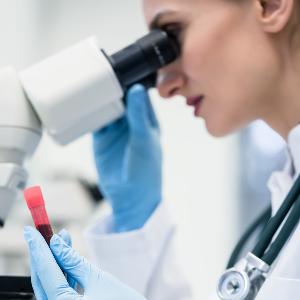 Eine Person mit Laborkittel und Gummihandschuhen sieht durch ein Mikroskop | © Arne Trautmann Eine Person mit Laborkittel und Gummihandschuhen sieht durch ein Mikroskop