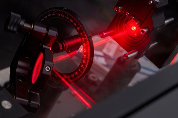 Nahaufnahme eines Laboraufbaus mit einem roten Laser | © Jan Greune / LMU Nahaufnahme eines Laboraufbaus mit einem roten Laser