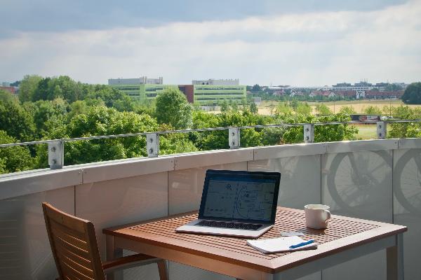 Aufnahme einer Terrasse und einem Tisch, auf dem eine Tasse und ein Laptop stehen