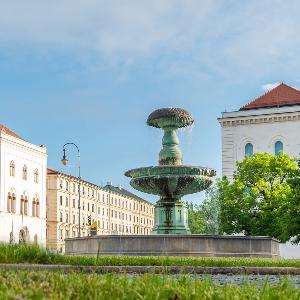 Eine grüne Wiese mit Bäumen und einem Brunnen darauf