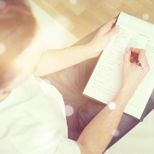 Eine Person wird von oben beim Ausfüllen eines Formulars gezeigt.
