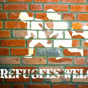 Grafitti mit der Botschaft Refugees welcome auf einer Mauer.