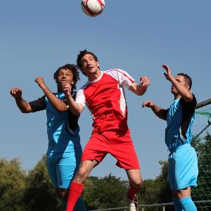Drei Personen spielen Fußball.