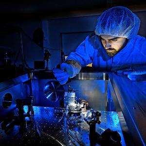Ein Mann mit Schutzanzug macht einen Versuch in einem Physik Labor