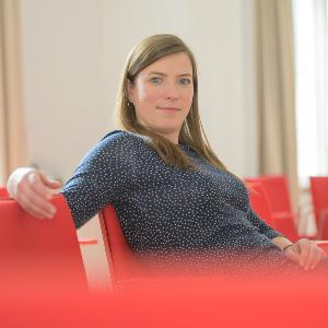 Dr. Antonia Misch sitzt in einem Raum mit roten Stühlen