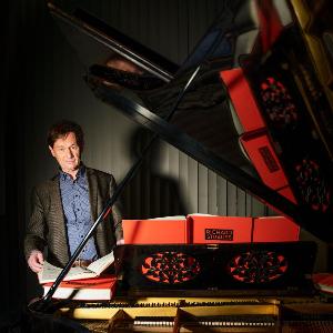 Professor Hartmut Schick steht vor einem Klavier.