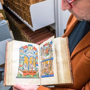 Person mit aufgeschlagenem Buch in der Hand