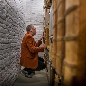 Dr. Sven Kuttner in der Hocke vor Bücherregal